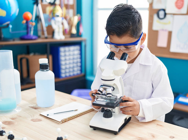 Entzückende hispanische Junge Student mit Mikroskop im Labor Klassenzimmer - Foto, Bild