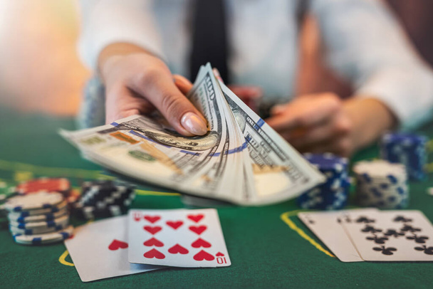美しい女性プレーヤーはお金のためのチップをカウントし、カジノでポーカーゲーム中に上昇します。ギャンブルの概念。女だ。隔離された - 写真・画像