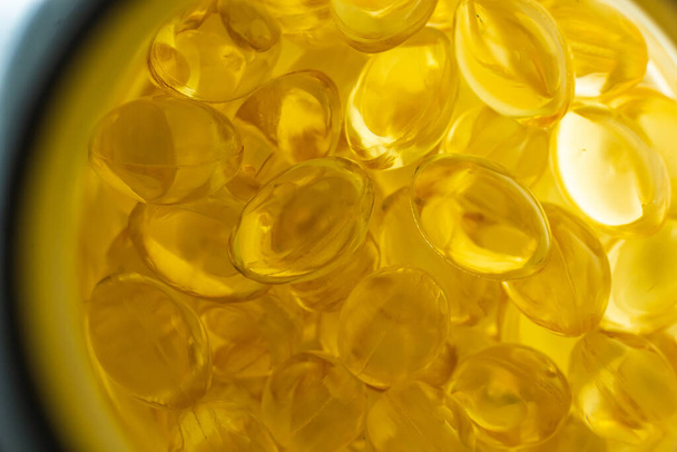 πολλά κίτρινα καψάκια ζελατίνης σε ελαφρύ φόντο. omega viramins, κοντινό πλάνο, μακροεντολή. - Φωτογραφία, εικόνα