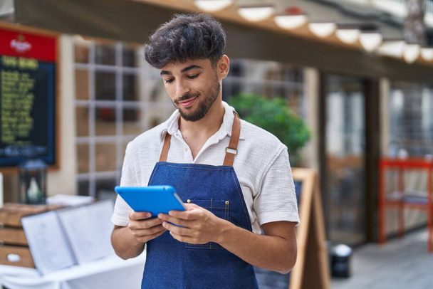 Young arab man waiter using touchpad working at restaurant - Fotó, kép