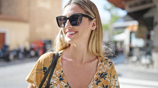 Молода блондинка посміхається впевнено носити сонцезахисні окуляри на вулиці
 - Фото, зображення