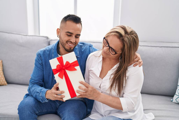 Man and woman mother and son surprise with gift hugging at home - Φωτογραφία, εικόνα