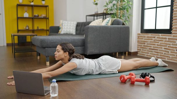 Joven hermosa mujer hispana haciendo yoga con laptop en casa - Foto, imagen