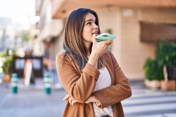 Young beautiful hispanic woman talking on smartphone with serious expression at street - Photo, image