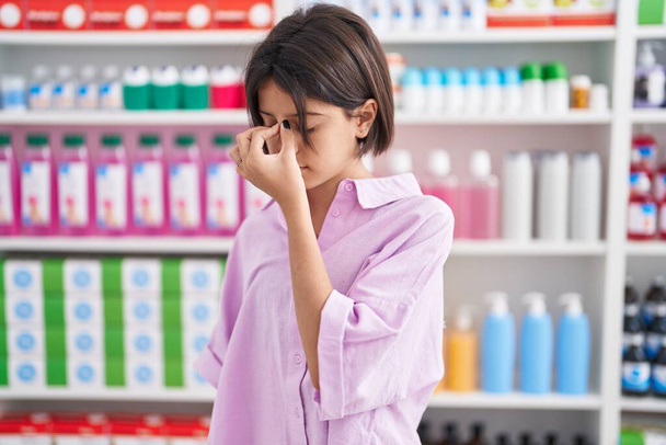 Fiatal lány a gyógyszertárban fáradt dörzsölés orr és szem érzés fáradtság és fejfájás. stressz és frusztráció fogalma.  - Fotó, kép