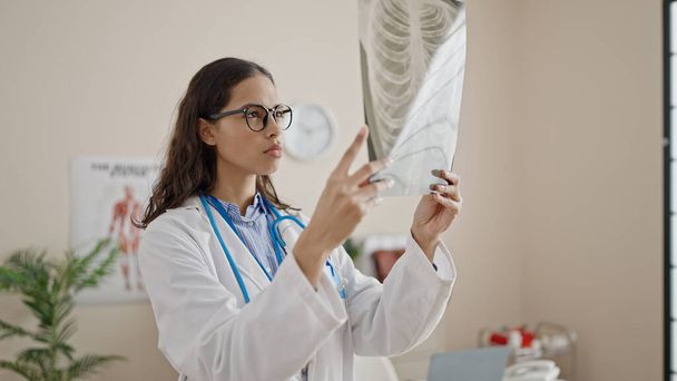 Joven hermosa mujer hispana médico mirando rayos X en la clínica - Foto, Imagen