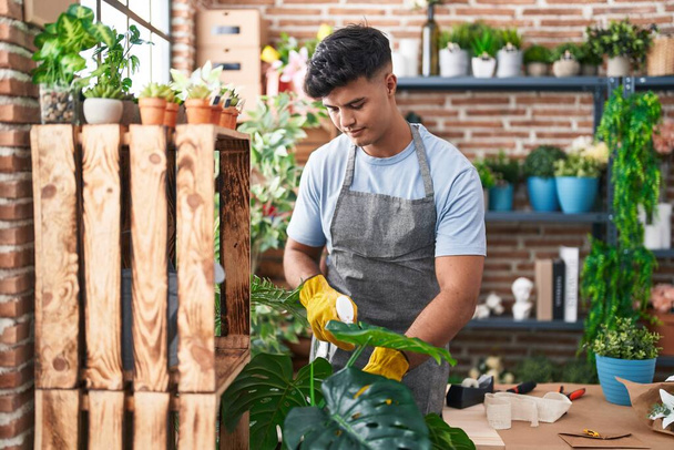 Young hispanic man florist using difusser working at flower shop - 写真・画像