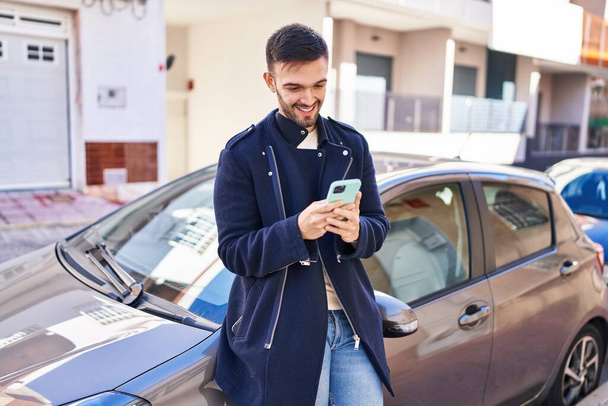 Young hispanic man using smartphone leaning on car at street - Φωτογραφία, εικόνα