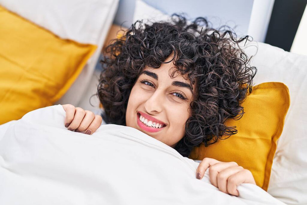 Mladý Blízký východ žena usměvavá sebevědomě ležet na posteli v ložnici - Fotografie, Obrázek