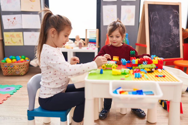 Ragazze adorabili che giocano con i blocchi di costruzione seduti sul tavolo all'asilo - Foto, immagini