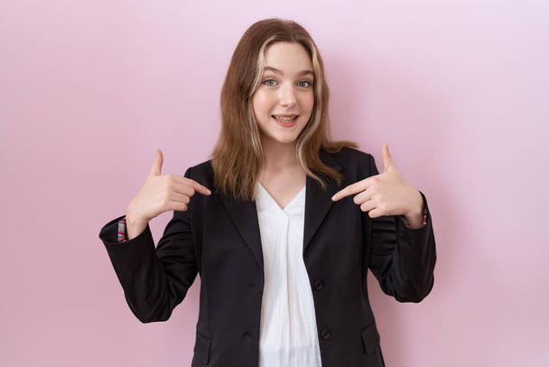 Young caucasian business woman wearing black jacket looking confident with smile on face, pointing oneself with fingers proud and happy.  - Фото, изображение