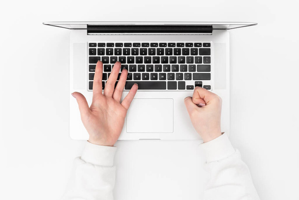 Laptop fehér háttérrel és női kezekkel, felülnézetből. A távmunka, az online tanulás, az üzleti élet és a technológia használata. - Fotó, kép