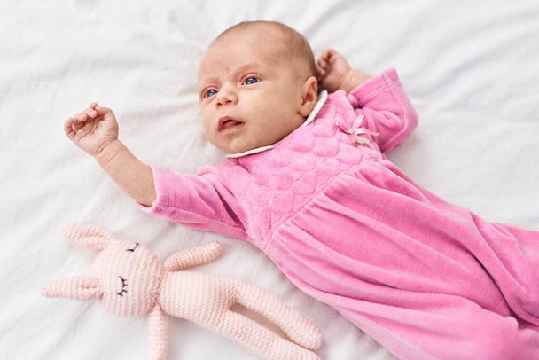 Imádnivaló spanyol baba fekszik az ágyon játékkal a hálószobában - Fotó, kép