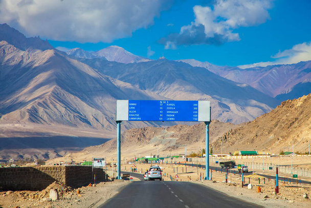 Weg naar Lamayuru, Ladakh stad in India.Stedelijk landschap met bergachtige achtergrond.Toerist met auto met verkeersbord.Blauwe lucht met bewolkt landschap.Landschap van Azië. - Foto, afbeelding