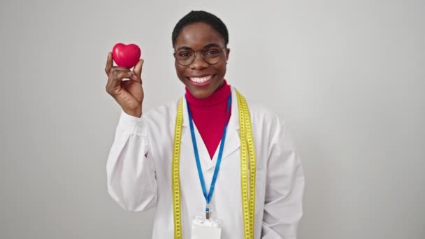 Femme afro-américaine diététicienne faisant pouce vers le haut tenant le cœur sur fond blanc isolé - Séquence, vidéo
