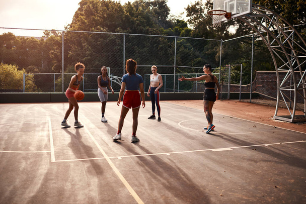 Trying to get as many points in. a diverse group of sportswomen playing a competitive game of basketball together during the day - Photo, Image
