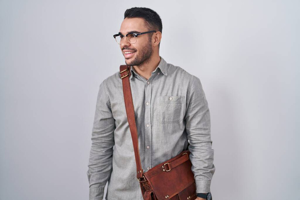 若いヒスパニック系の男性のスーツケースを離れて顔に笑顔で側に見て着て、自然な表情。自信を持って.  - 写真・画像