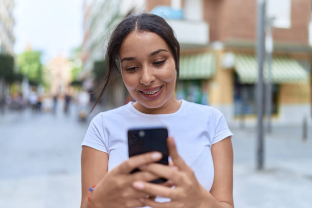 Young arab woman smiling confident using smartphone at street - Photo, Image