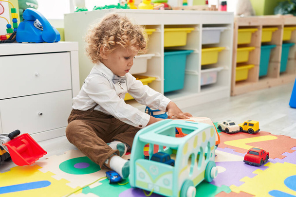 Чарівний блондинка малюк грає з машинами іграшка сидить на підлозі в дитячому саду
 - Фото, зображення