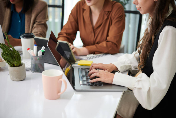 Image recadrée de femmes d'affaires travaillant sur des ordinateurs portables à la table de bureau - Photo, image