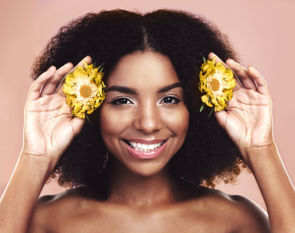 Πορτρέτο της ευτυχισμένης γυναίκας, περιποίηση μαλλιών και ομορφιά με κίτρινα λουλούδια στο φόντο στούντιο. Αφρικανικό μοντέλο, φυσικά φυτά περιποίησης και μαργαρίτες στην Αφρική για βιώσιμα καλλυντικά, ανθική αισθητική και χαμόγελο. - Φωτογραφία, εικόνα