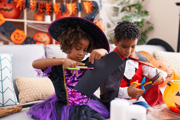 Uroczy afrykański chłopiec i dziewczyna mając halloween party cięcia papieru w domu - Zdjęcie, obraz