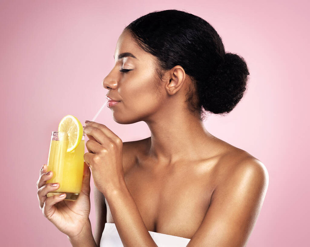 Face of woman, orange juice and drink in studio, pink background and detox for healthy skincare. African model, citrus smoothie and vitamin c fruits for nutrition benefits, natural beauty or wellness. - 写真・画像
