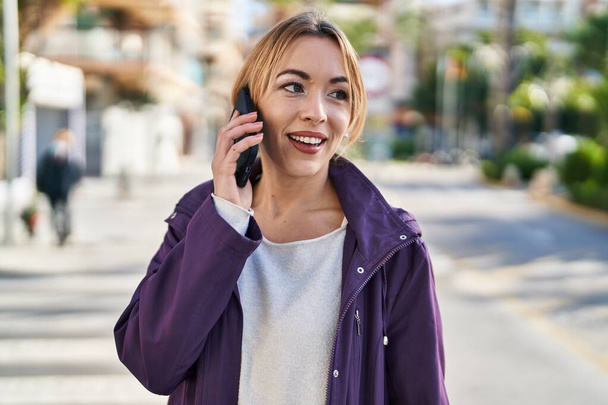 Giovane donna sorridente fiducioso parlando sullo smartphone in strada - Foto, immagini