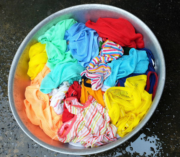 Kolorowe ubrania dziecka nasączone w proszku rozpuszczania wody detergentu na podłodze cementowej.pralnia koncepcja suche i czyszczenia pielęgnacji ubrań - Zdjęcie, obraz
