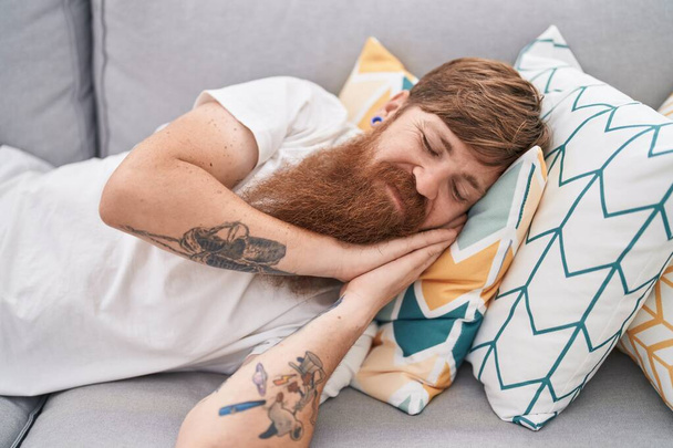 Young redhead man lying on sofa sleeping at home - Photo, Image