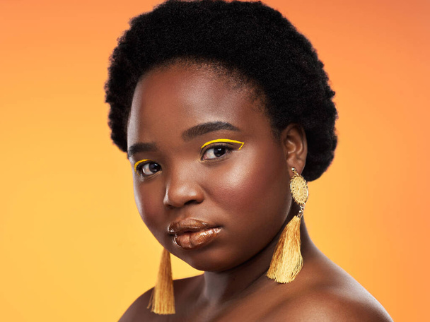 Gold looks good on her. Studio shot of a beautiful young woman posing against an orange background - Photo, Image