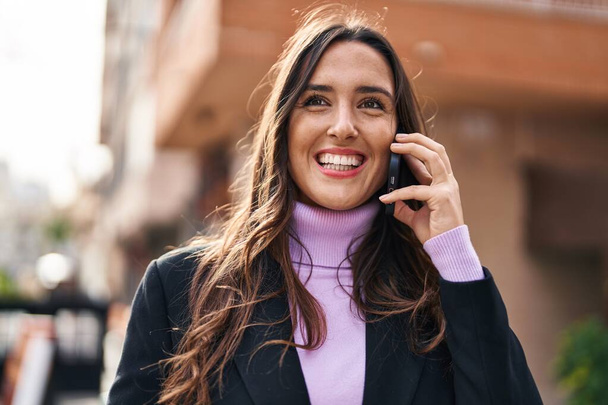 Giovane donna ispanica sorridente fiducioso parlando sullo smartphone in strada - Foto, immagini