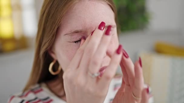 Mujer rubia joven rascarse los ojos sentado en el sofá en casa - Metraje, vídeo
