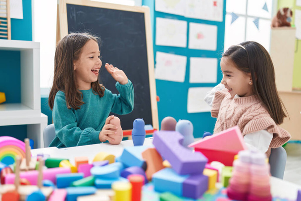 Adorable girls playing with construction blocks high five at kindergarten - Photo, Image