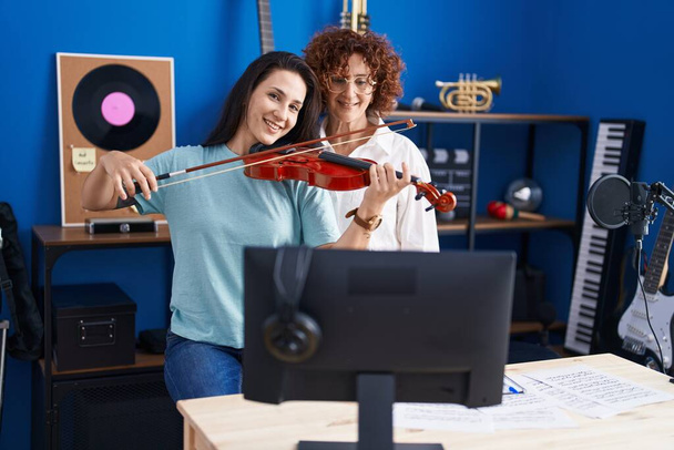 Две женщины учатся игре на скрипке в музыкальной студии - Фото, изображение