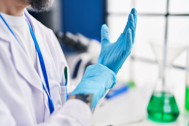 Fiatal kopasz tudós kesztyűt visel a laboratóriumban - Fotó, kép
