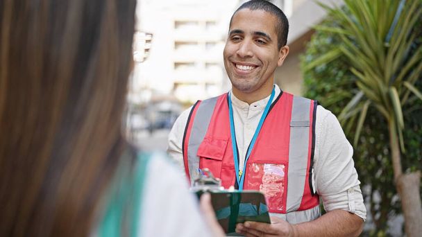 Jovem hispânico voluntário falando com pessoa na rua - Foto, Imagem