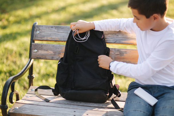 Мальчик-подросток в белой рубашке использует банк питания для зарядки своего смартфона. Низкая батарея на смартфоне
. - Фото, изображение