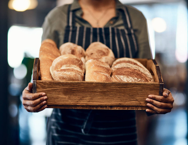 Can I interest you in a sample. a woman holding a selection of freshly baked breads in her bakery - Photo, image