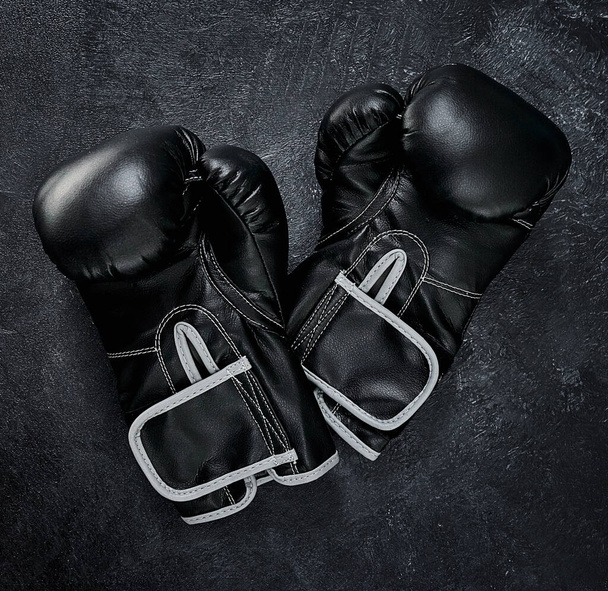 Put your hands up. High angle shot of a pair of boxing gloves placed together on top of a dark background inside of a studio - Photo, image