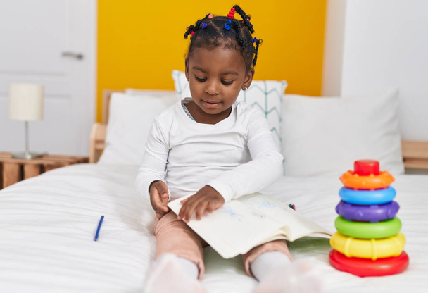 afroamericano ragazza seduta su letto lettura libro a camera da letto - Foto, immagini