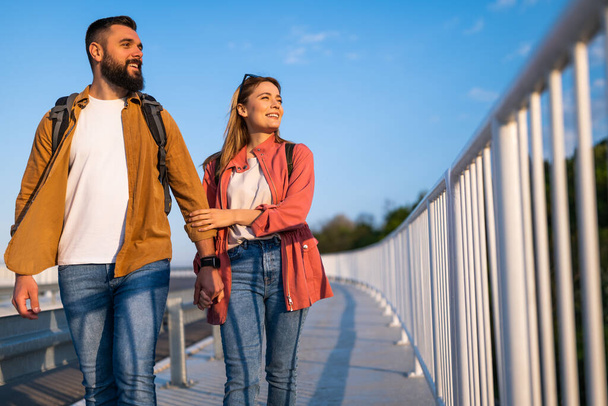Ευτυχισμένο ζευγάρι κρατιέται χέρι χέρι και περπατά σε πεζόδρομο. Τουρίστες είναι αξιοθέατα στην πόλη. - Φωτογραφία, εικόνα