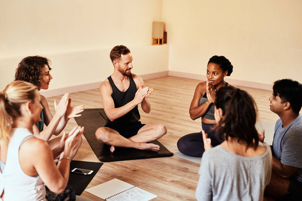 Хорошее здоровье это то, что стоит отметить. группа молодых мужчин и женщин хлопает во время урока йоги - Фото, изображение