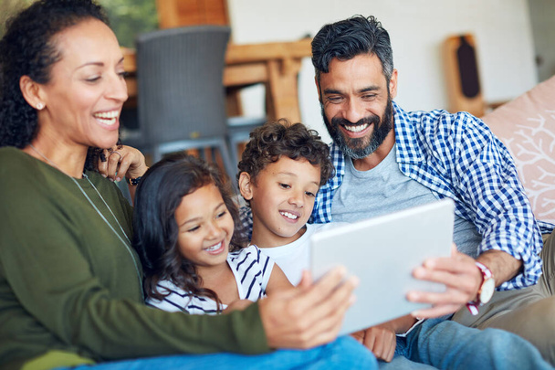 デジタルタブレット、自宅でストリーミング、サブスクリプション、ゲームアプリとソファの上でリラックスして幸せな家族。インターネットの楽しさと絆のために両親を持つオンライン、エンターテイメント、子供たち. - 写真・画像