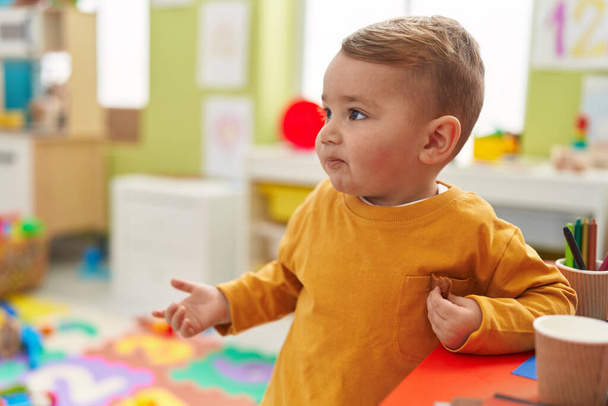 Adorable blond toddler standing with relaxed expression at kindergarten - Foto, Imagen