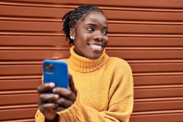 African american woman smiling confident using smartphone at street - Photo, Image
