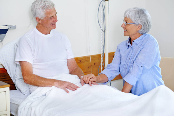 На краще чи гірше. хворий чоловік у лікарняному ліжку втішається дружиною
 - Фото, зображення