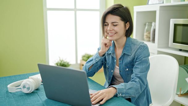 若いです白人女性を使用してノートパソコンを使用してテーブルの上に家に座って - 写真・画像