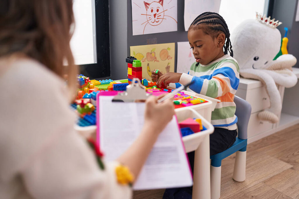 African american boy playing with construction blocks having psychotherapy at kindergarten - Foto, imagen