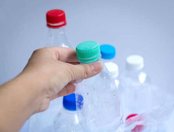 Hand putting a plastic bottle inside a plastic bag filled with bottles. Recycle or trash concept. - Fotó, kép